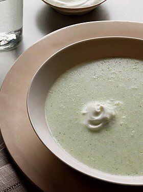 a bowl of soup on a table next to a glass of water and a spoon