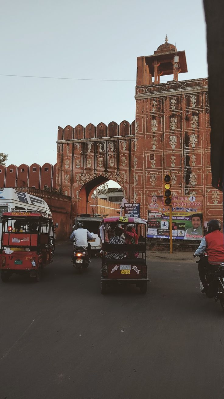 three vehicles driving down the road in front of an old building