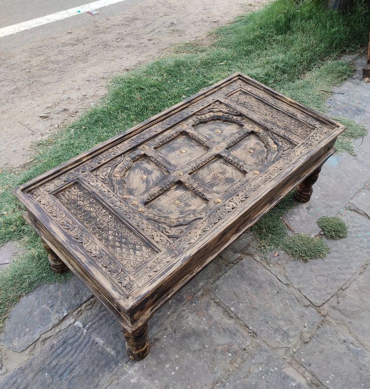 an old wooden table sitting on the ground in front of some grass and dirt area