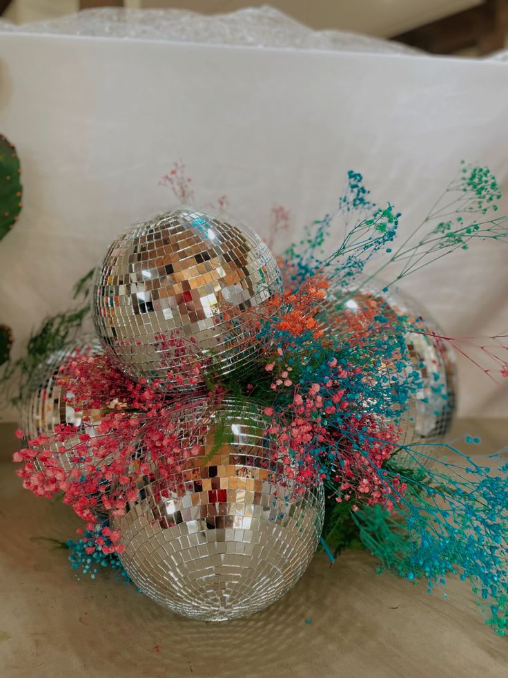 three disco ball vases filled with colorful flowers