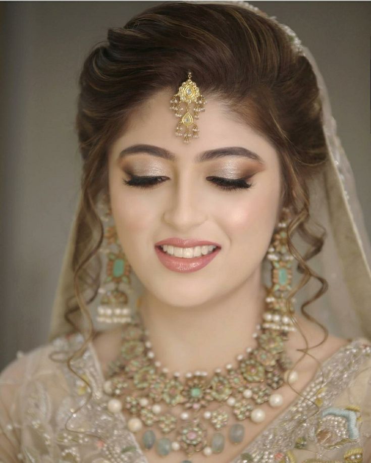 a woman in a bridal outfit with pearls and jewels on her head, smiling at the camera