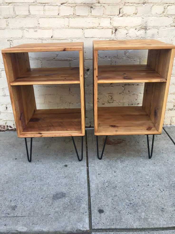 two wooden bookshelves sitting on top of each other next to a brick wall