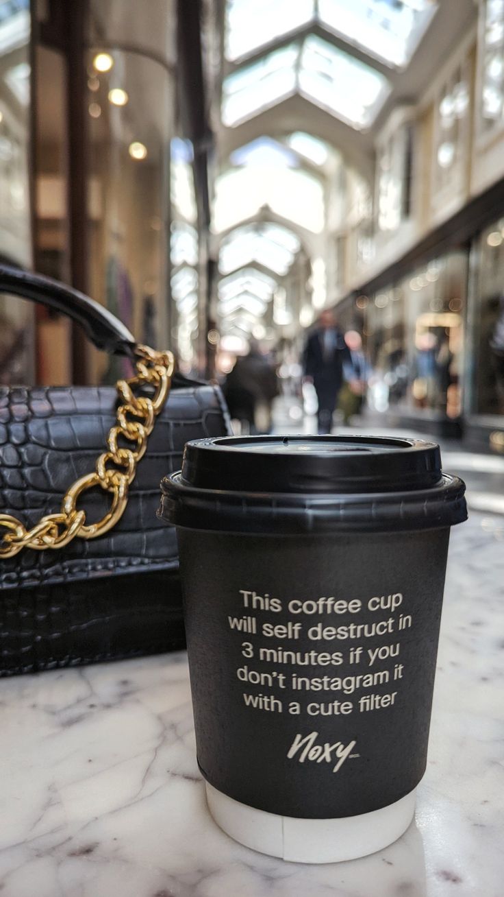 a coffee cup sitting on top of a table next to a handbag and purse