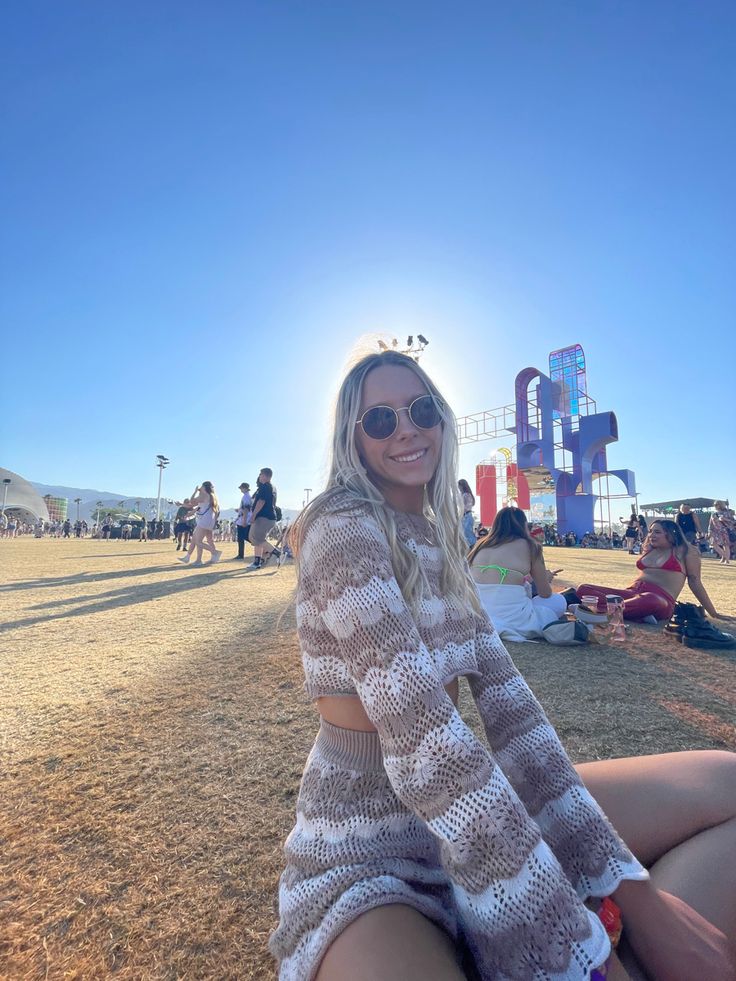 a woman sitting on the ground wearing sunglasses