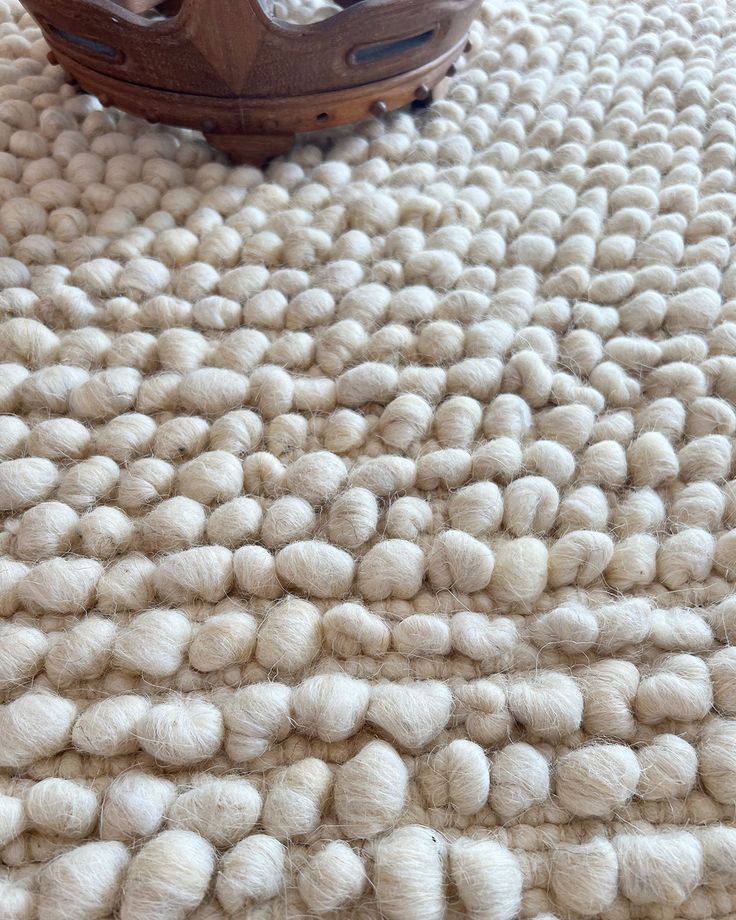 a wooden boat sitting on top of a pile of white wool yarn covered flooring