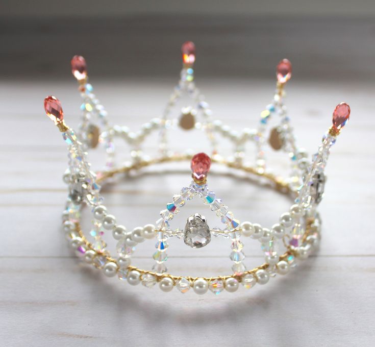 a tiara made out of pearls and other beads on a white table with wood flooring