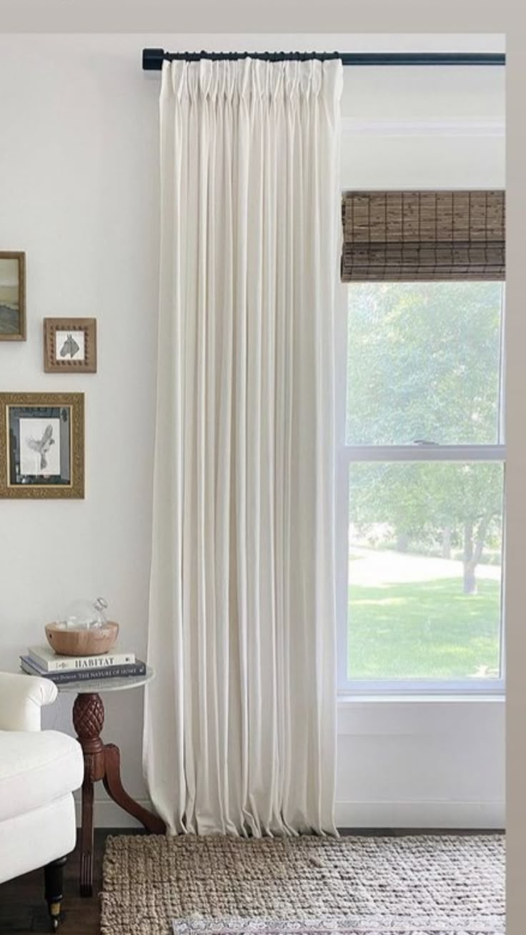 a living room with white curtains and pictures on the wall