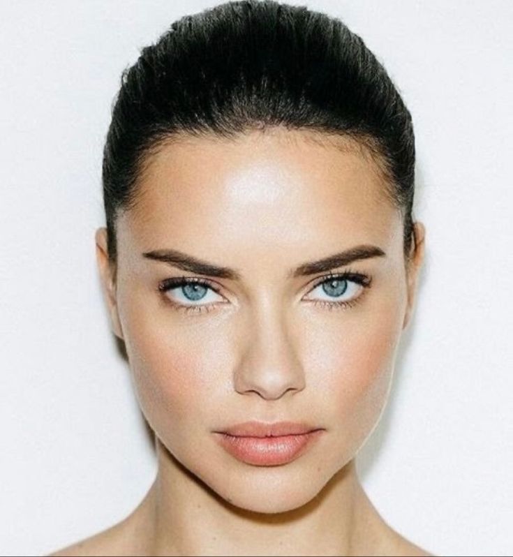 a woman with blue eyes is posing for the camera and has her hair pulled back into a bun