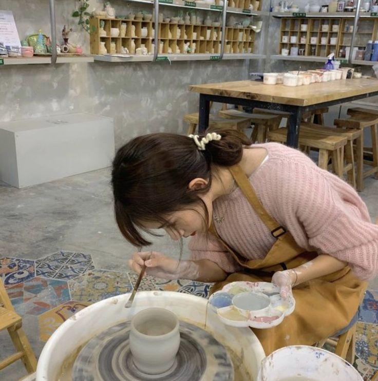 a woman is working on a pottery wheel