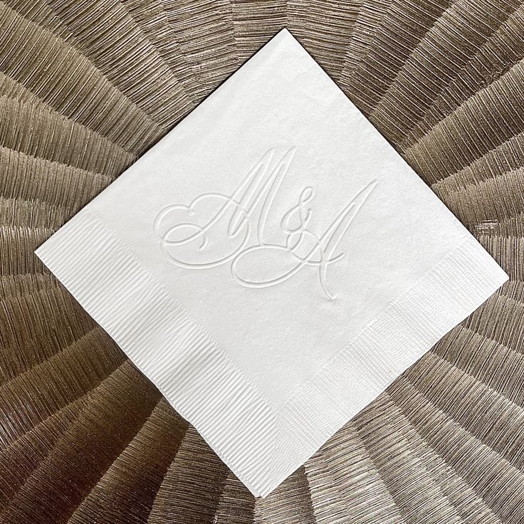 the monogrammed napkin is on top of an intricately designed piece of cloth