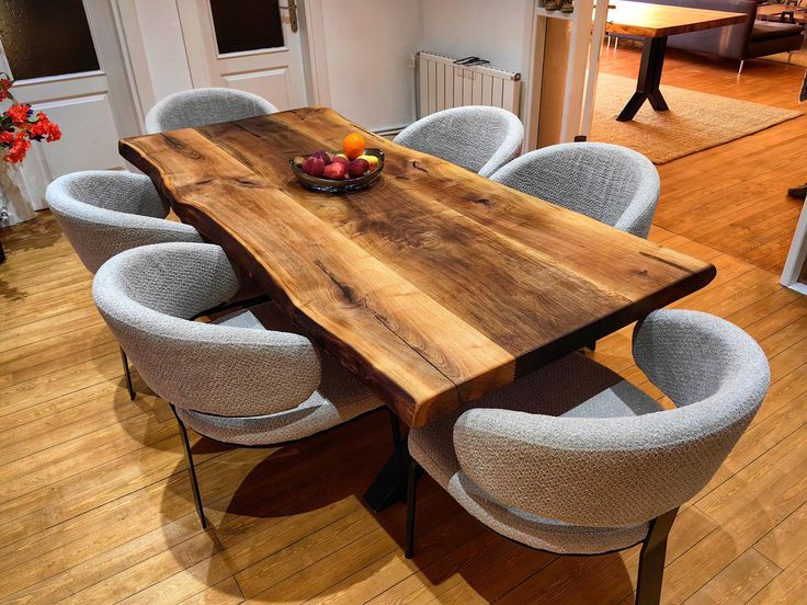 a wooden table surrounded by white chairs in a room with hard wood floors and walls