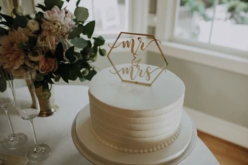 a white wedding cake sitting on top of a table next to a vase with flowers