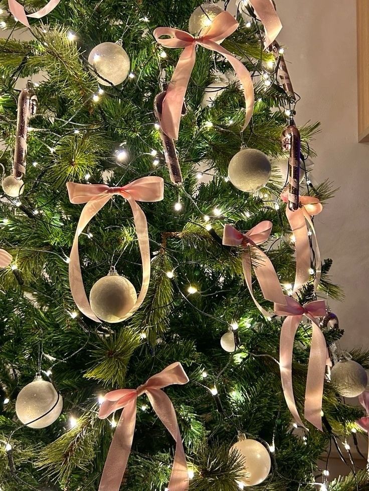 a decorated christmas tree with pink ribbon and baubles hanging from it's sides