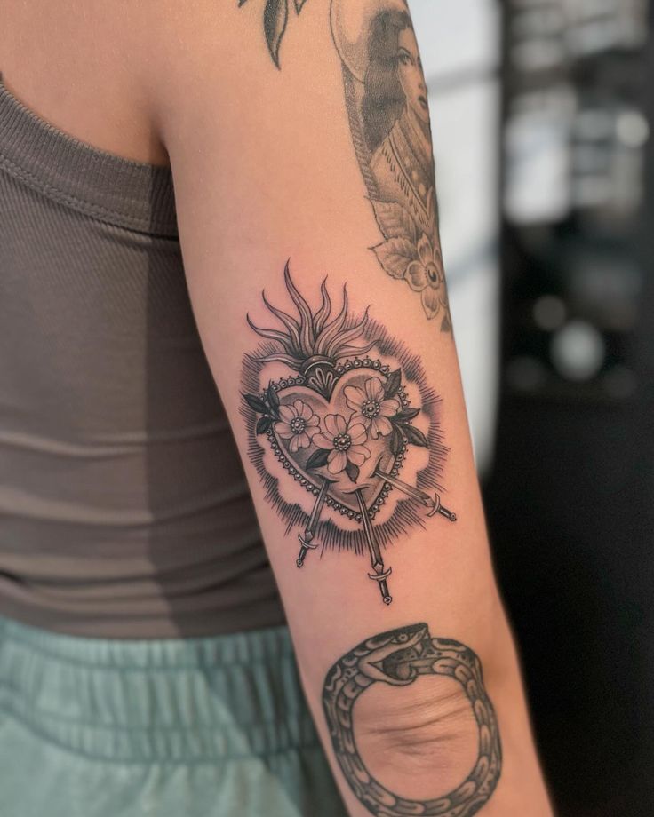 a woman's arm with tattoos on it and a heart in the middle, surrounded by other items