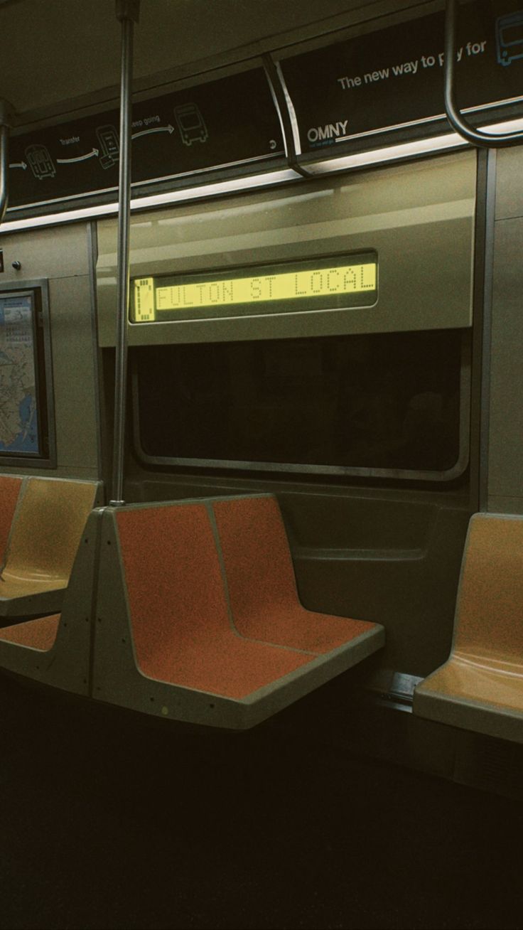 an empty subway car with red seats and yellow backlights on the seat area is seen in this image