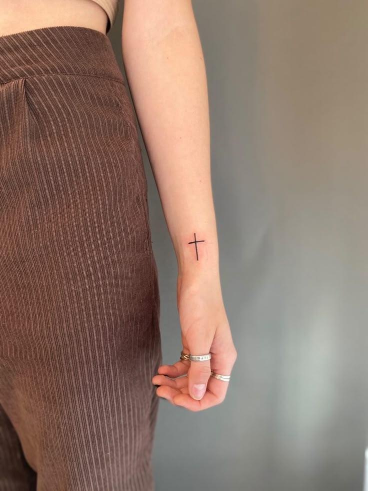 a woman with a cross tattoo on her left hand and a ring in her other hand