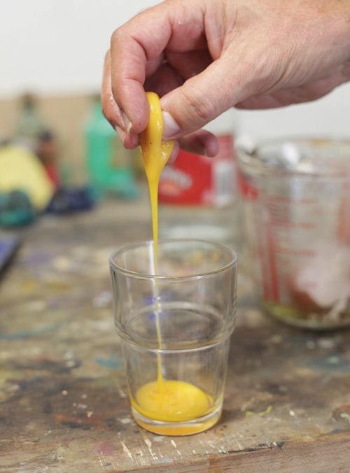 a person pouring liquid into a glass on top of a table