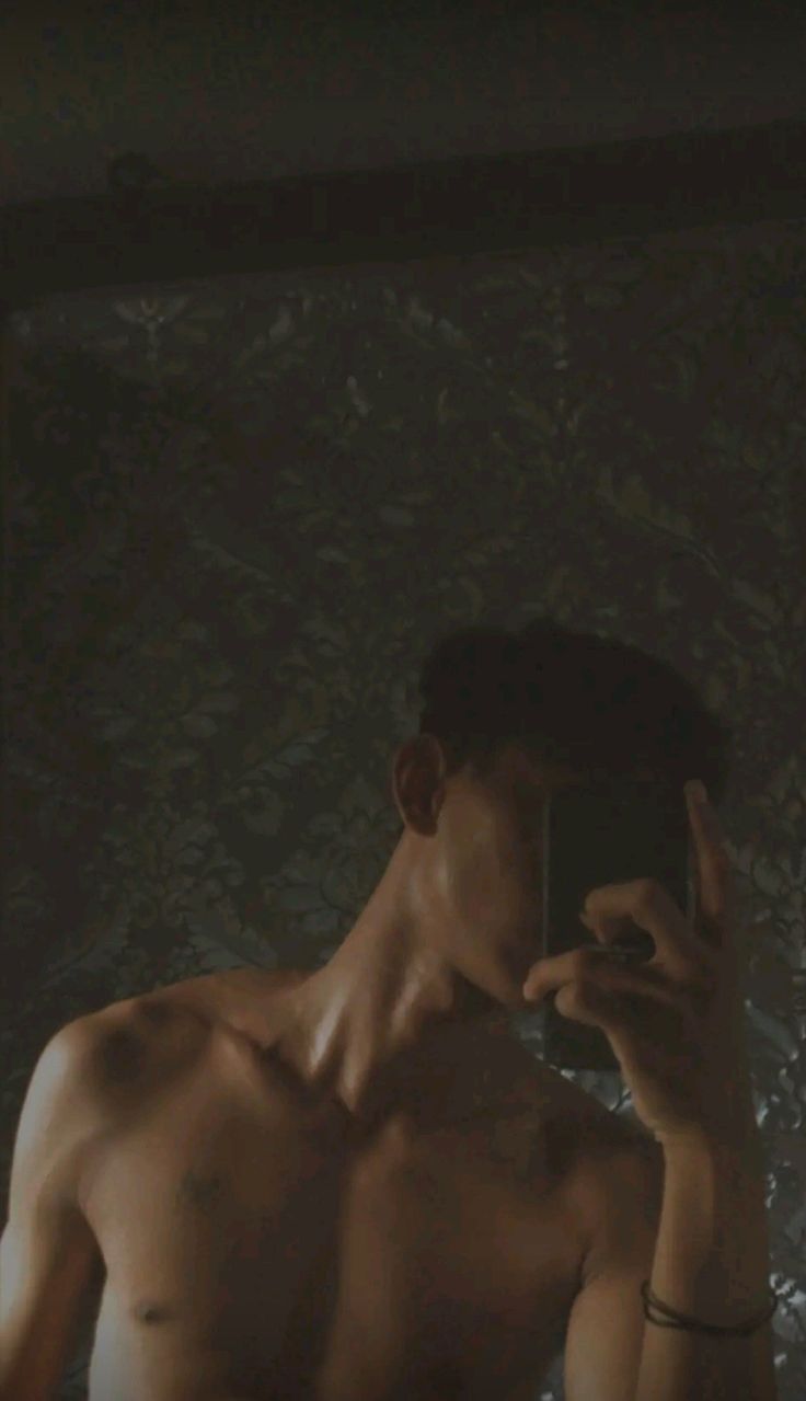 a shirtless man taking a selfie in front of a mirror with his cell phone