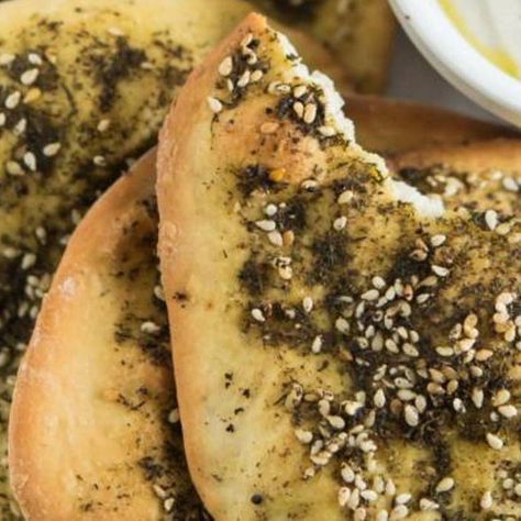 sesame seed bagels are piled on top of each other with dipping sauce in the background