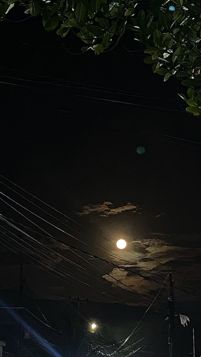 the full moon is shining brightly in the night sky above power lines and telephone poles