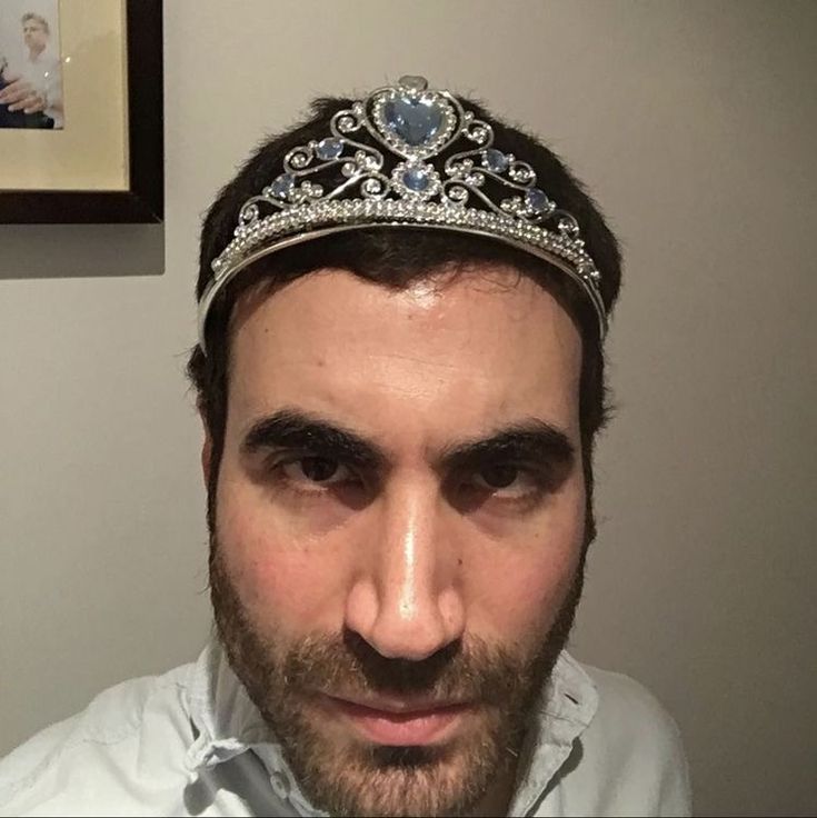 a man with a tiara on his head looking at the camera while wearing a dress shirt