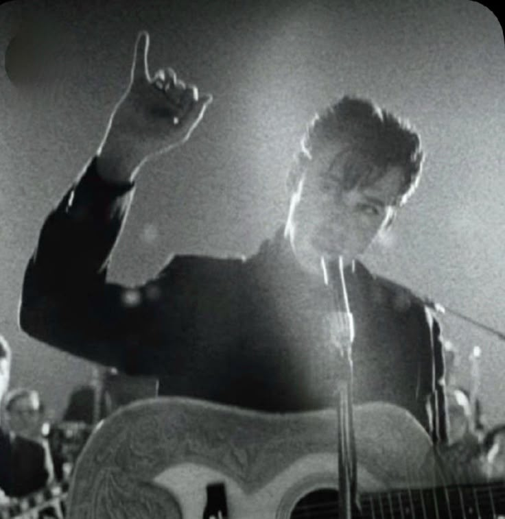 a man holding a guitar while standing in front of a microphone