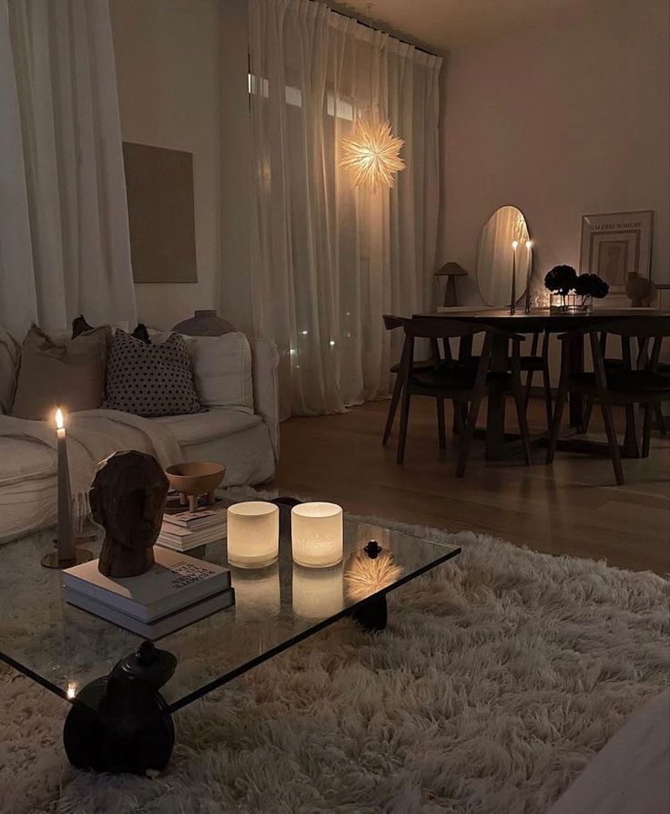 a living room filled with furniture and candles on top of a coffee table in front of a window