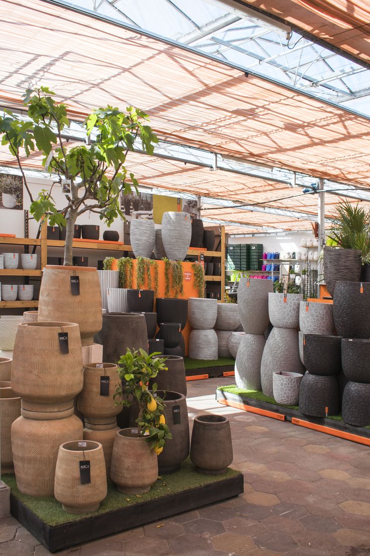 a room filled with lots of potted plants and pots sitting on top of each other