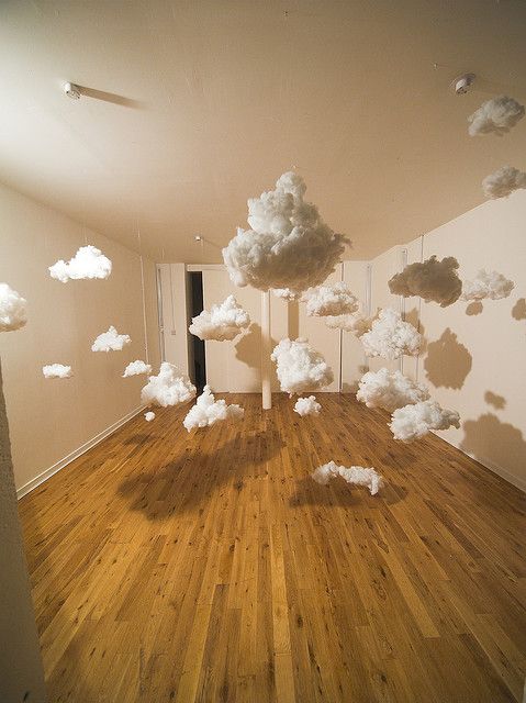 an empty room with wooden floors and white clouds floating in the air above it,