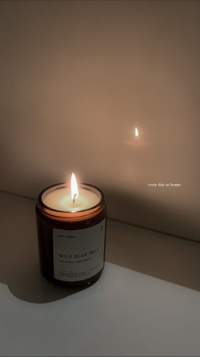 a lit candle sitting on top of a white table next to a wall and window