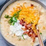 a bowl filled with soup and cheese on top of a blue cloth next to a spoon