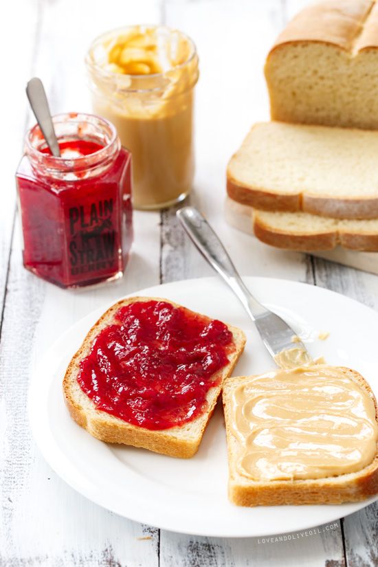 peanut butter and jelly sandwich on a white plate with jam in a jar next to it