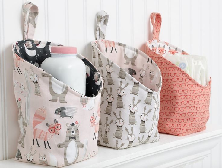 three storage bins on top of a white mantle holding bottles and diapers in them