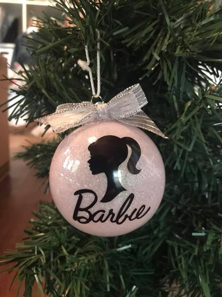 a bauble ornament hanging from a christmas tree with a bow on it