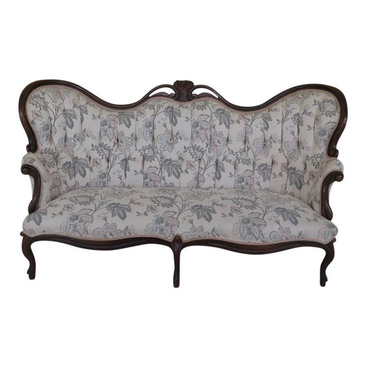 an antique style couch with floral fabric on it's back and arms, sitting in front of a white background