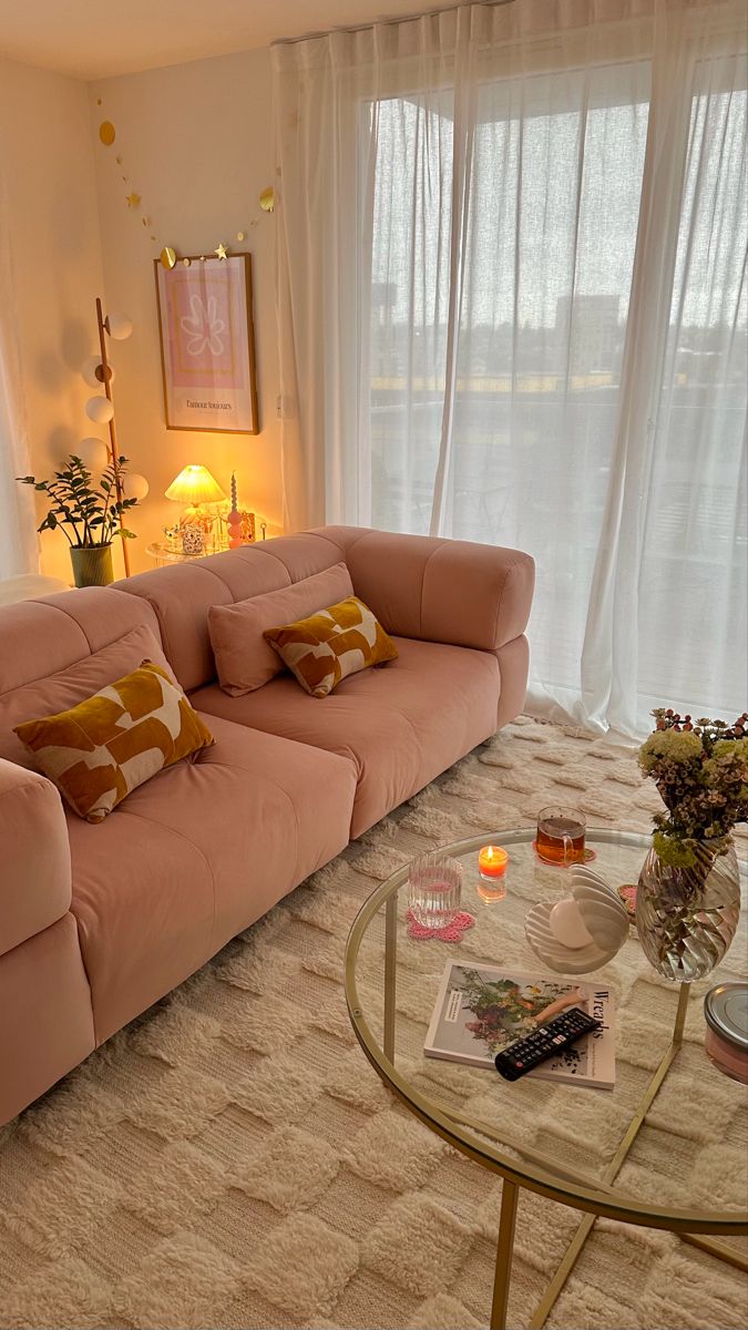 a living room filled with furniture next to a window covered in white curtains and drapes