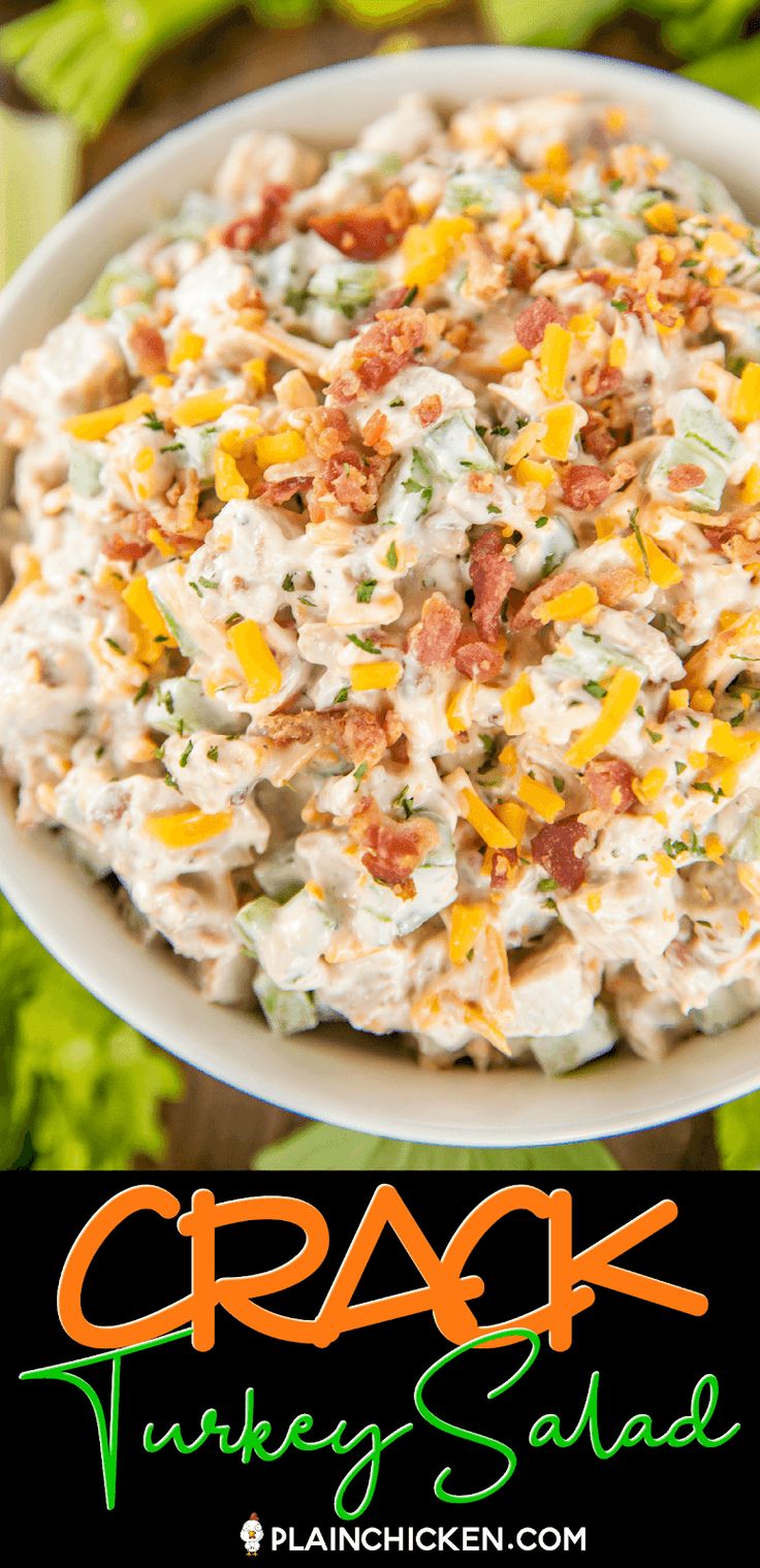 a white bowl filled with chicken salad next to lettuce and carrots on the side