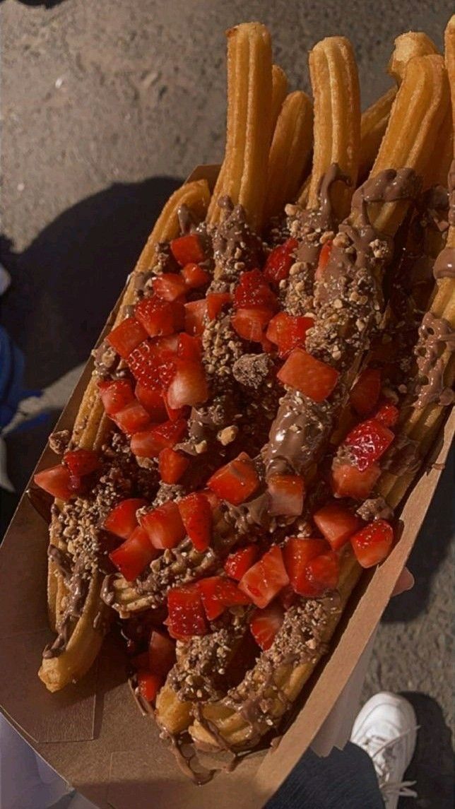 a hot dog covered in toppings and surrounded by french fries, strawberries, and ketchup