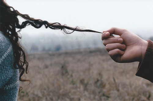 two people holding hands in the middle of a field