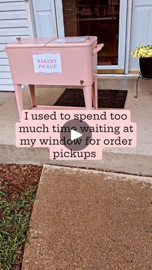 a pink box sitting on top of a sidewalk next to a flower potted plant