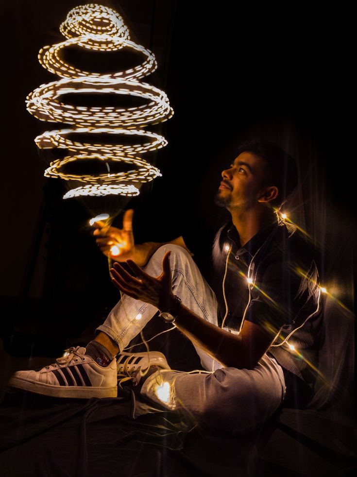 a man sitting on the floor with headphones in his hands and lights coming out of his ears