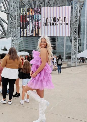 a woman in a pink dress and white boots posing for the camera at an event