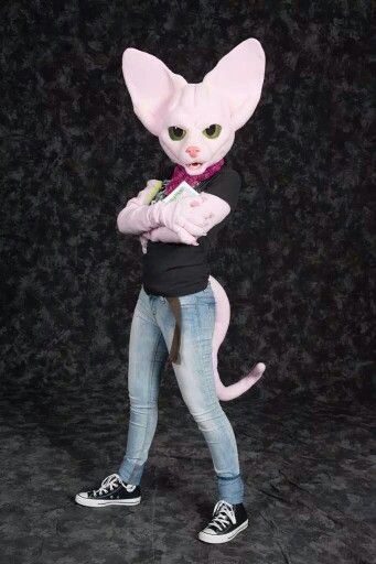 a woman in jeans and sneakers is dressed up as a pink cat with green eyes