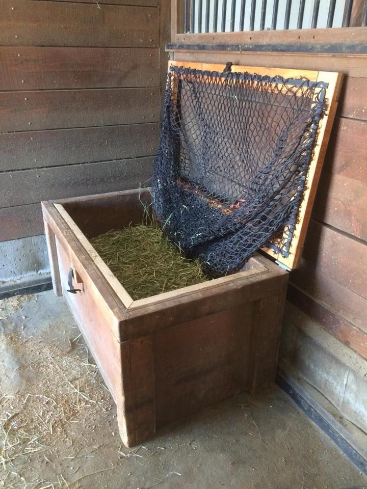 a wooden box with hay in it sitting on the ground next to a fence and wood wall