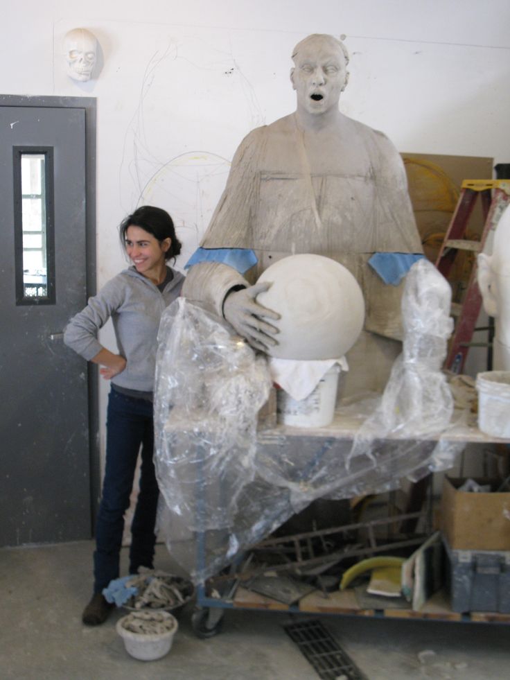 a woman standing next to a large statue in a room with plastic coverings on it