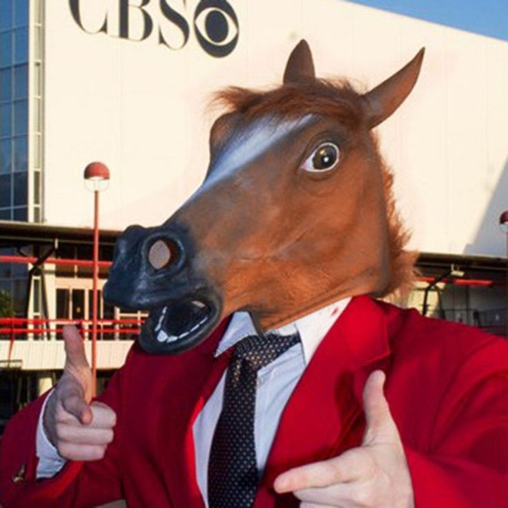 a man in a suit and tie with a horse mask on giving the thumbs up