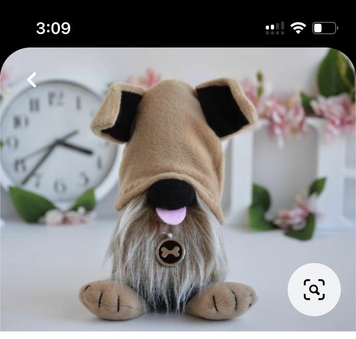 a small stuffed dog sitting in front of a clock