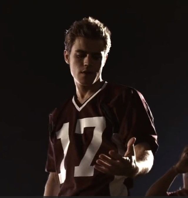 a young man in a football uniform holding his hand out