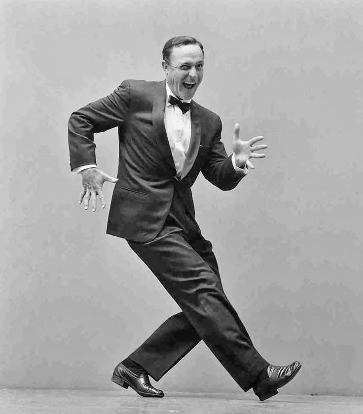 a man in a tuxedo is dancing with an inspirational quote on the wall behind him