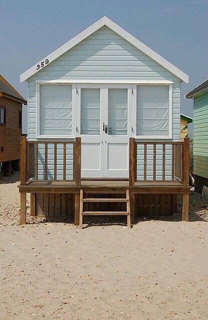 a small white house sitting on top of a sandy beach